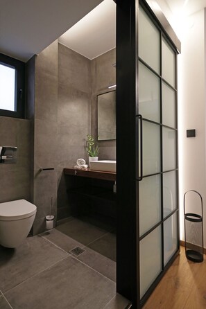 Un baño moderno con inodoro, lavamanos y mampara de vidrio.
