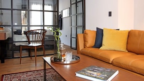 Una sala de estar moderna con un sofá de cuero, una silla de madera, una mesa de centro de vidrio y un libro.
