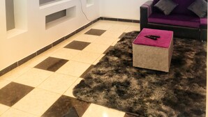 A modern living room with a flat-screen TV mounted on the wall, a purple sofa, and a fluffy rug on the floor. - Leila house (new apartment) (Alessandria)