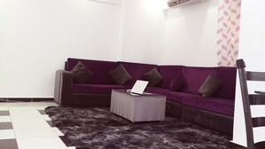 A modern living room with a purple sofa, a grey ottoman, and a black and white checkered floor. - Leila house (new apartment) (Alessandria)