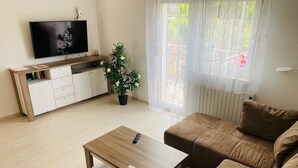 Un salon avec un téléviseur, un canapé, une table basse et une plante en pot.