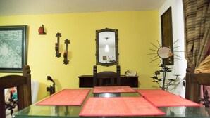 A dining area with a glass table set for four, a wooden chair, a mirror, and wall-mounted decorations. - Charming 1-bed Apartment in Armenia (Armenia)
