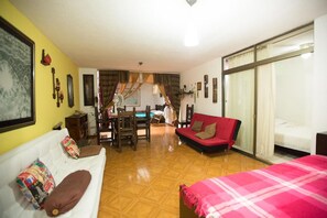 Cozy living space with a central dining area, featuring a bed, sofa, and dining table.