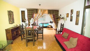 A room with a dining area, a red sofa, and a bed with curtains. - Charming 1-bed Apartment in Armenia (Armenia)