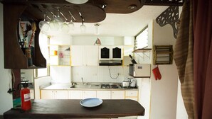 A compact kitchen with white cabinets, a stove, and a sink. There is a wooden countertop with a plate and a red fire extinguisher. - Charming 1-bed Apartment in Armenia (Armenia)