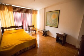 Ein Zimmer mit einem Bett, einem Sessel, einem kleinen Tisch und einem Bild an der Wand.