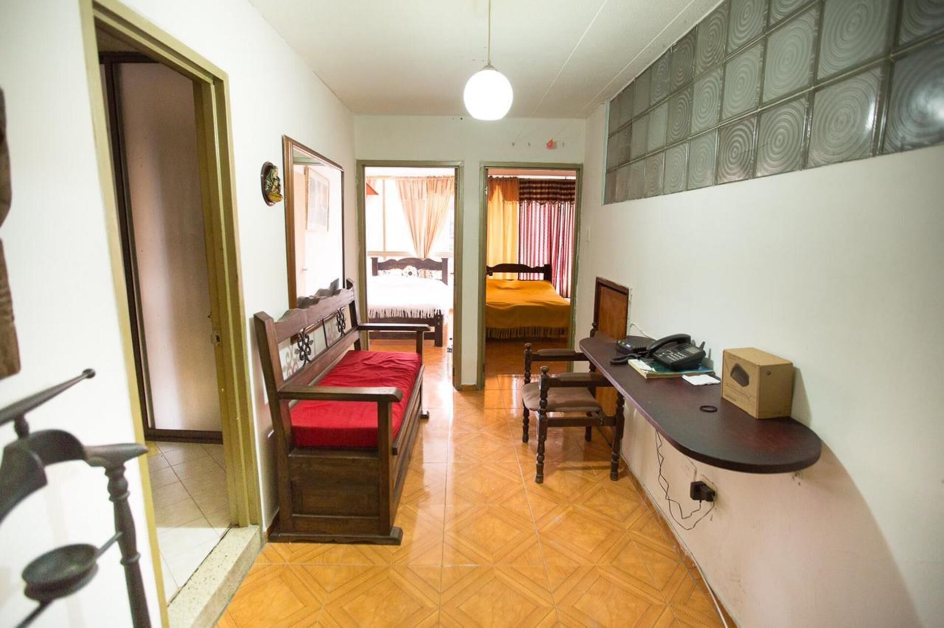A room with a bed, a desk with a telephone, and a chair.