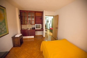 Ein Zimmer mit einem Bett, einem Schreibtisch mit Computer, einem Ventilator und einem Schrank.