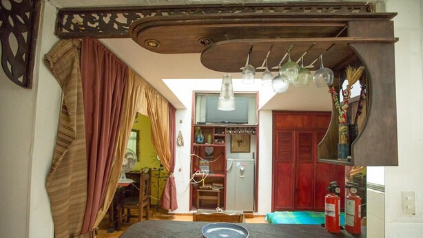 A compact kitchen with a wooden countertop, a fan, and a dining area with a table and chairs. - Charming 1-bed Apartment in Armenia (Armenia)