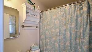 Une salle de bain équipée de toilettes, d’un lavabo et d’un rideau de douche orné d’un motif sur le thème de la mer.