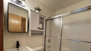 A bathroom with a white sink, a toilet, a mirror, and a shower enclosure. - 38 Piece Of Heaven Studio Bedroom Condo by RedAwning (Hatteras)