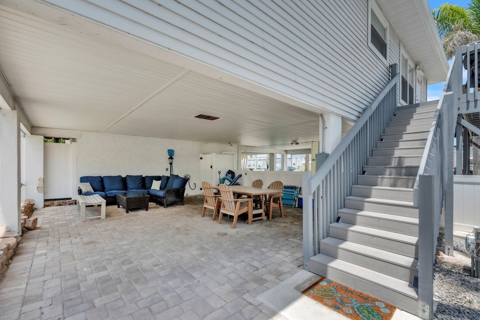 A covered patio area with a sofa, chairs, and a table.