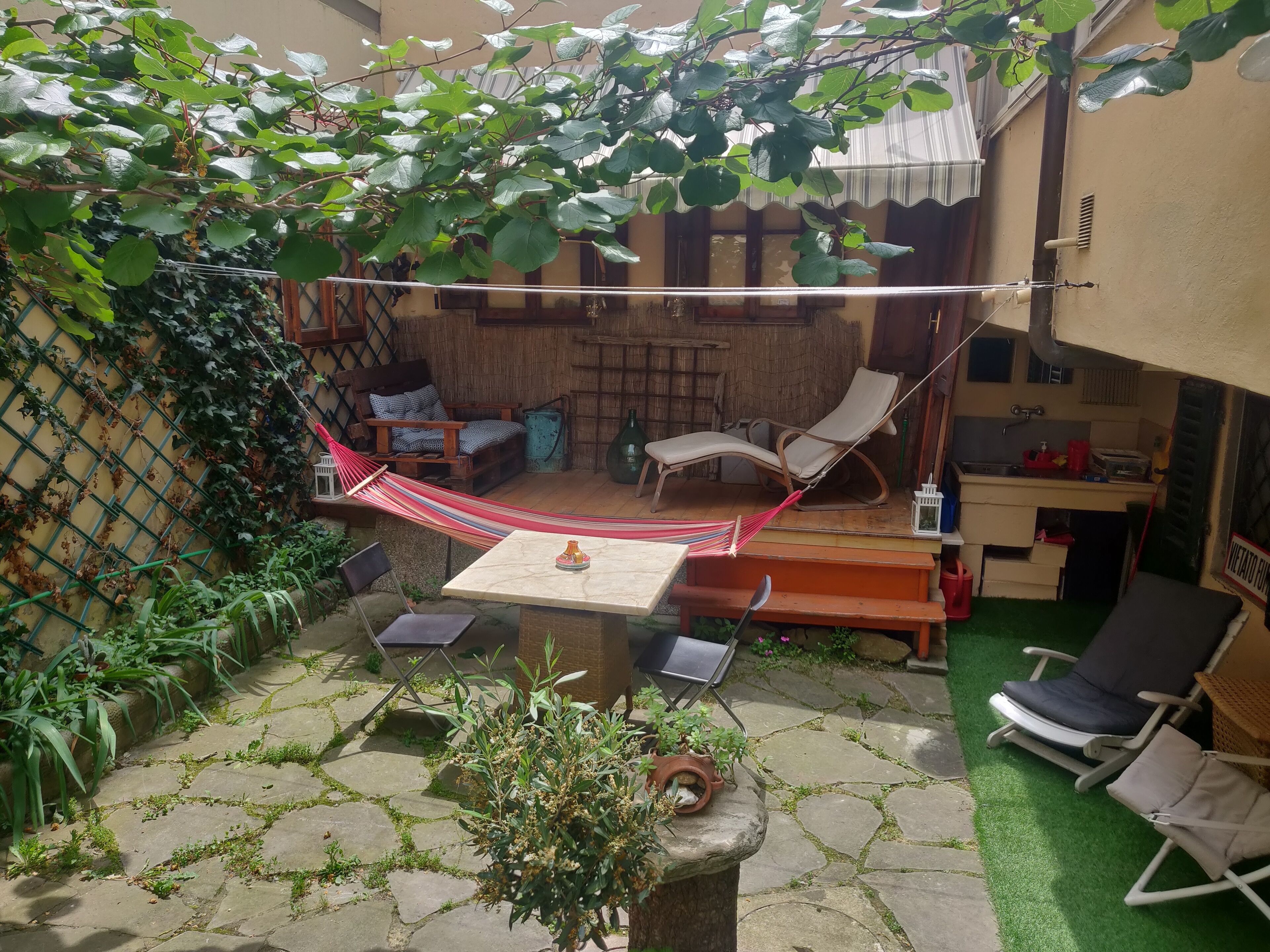 A patio with a hammock, outdoor furniture, and a small table.