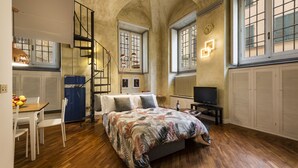 A bedroom with a bed, a desk, and a chair. There is a window with shutters and a radiator. - Cool Loft Deluxe by Dante House, Top Location (Florence)