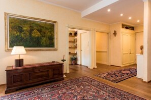 A hallway with a wooden console table, a large painting, and two patterned rugs on the floor.
