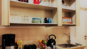 Une cuisine équipée d’une machine à café, d’une bouilloire et de différents ustensiles de cuisine posés sur le plan de travail.