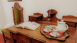Un bureau en bois, un livre ouvert, un plateau avec des tasses et une théière, et un miroir.