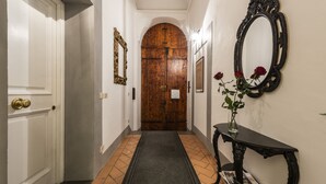 Ein Flur mit einer Holztür, einem Spiegel und einer Vase mit Blumen auf einer Konsole.