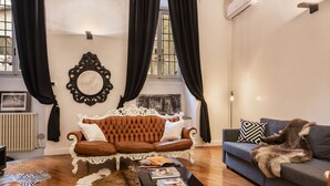 Ein Wohnzimmer mit einem braunen Ledersofa, einem blauen Sofa mit Felldecke, einem Couchtisch mit Büchern und einem Kuhfellteppich.