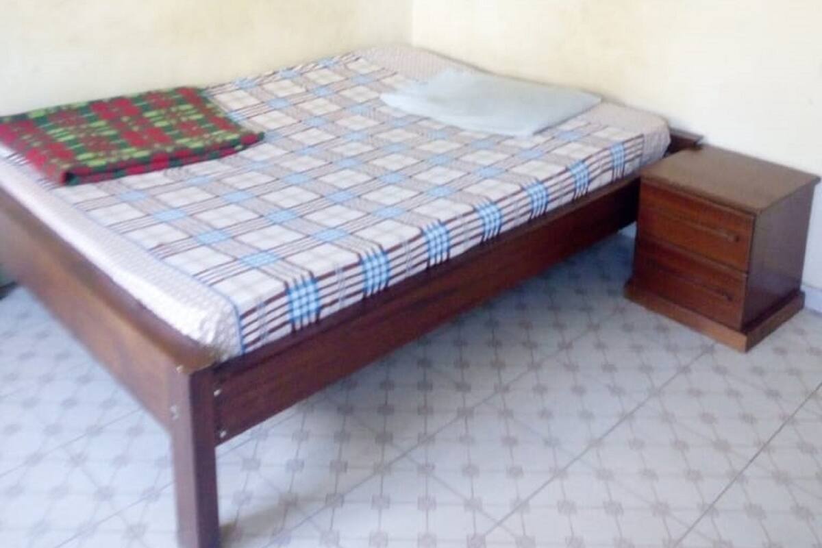 A bedroom with a bed, a wooden nightstand, and a blue mosquito net.