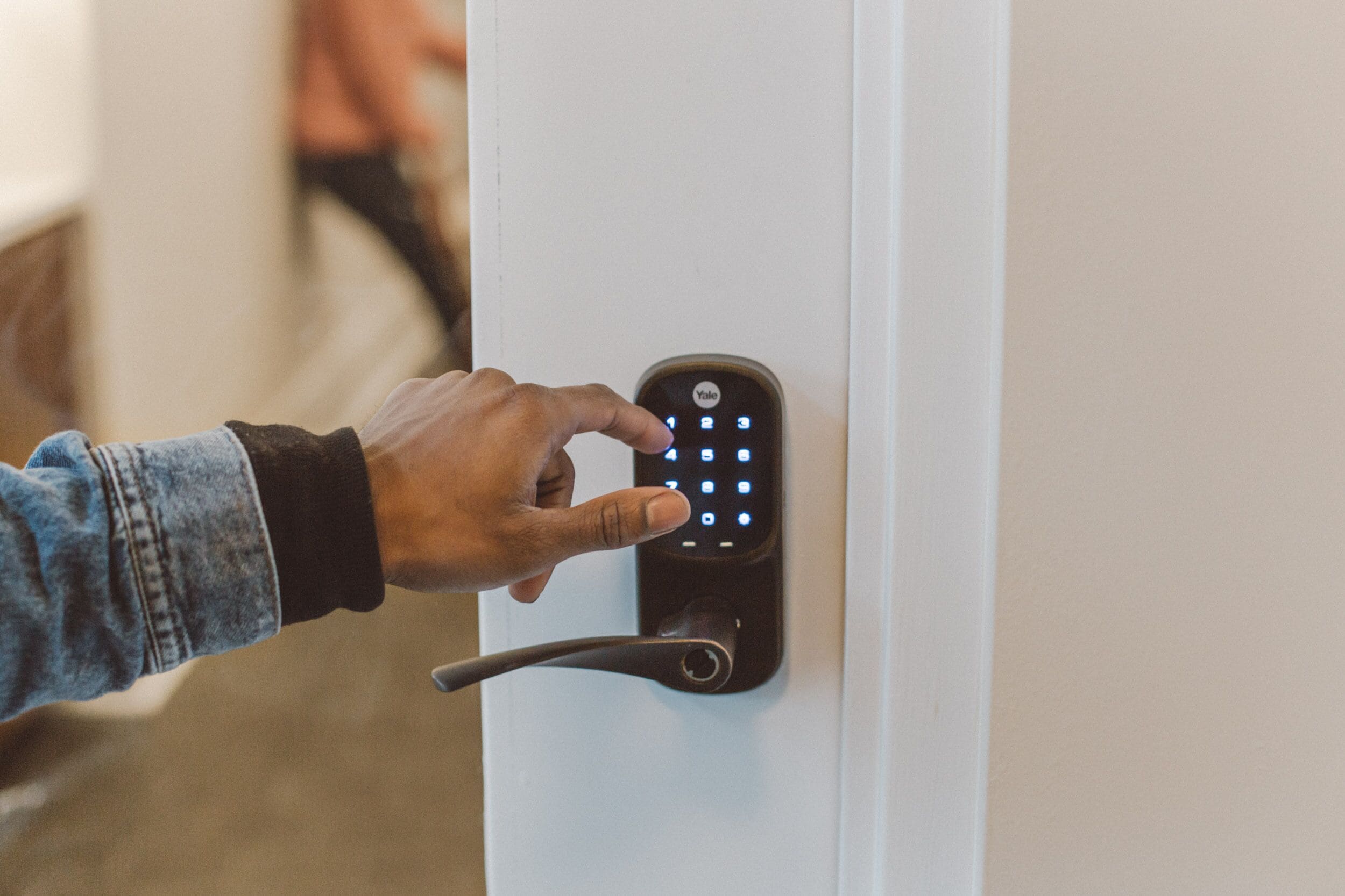 Una persona usando una cerradura inteligente Yale en una puerta.