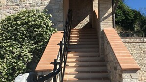 A stone staircase with a metal railing leading to a covered entrance. - La Dimora di Francesco (Assisi)