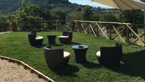 A grassy outdoor seating area with wicker furniture and a large canopy. - La Dimora di Francesco (Assisi)