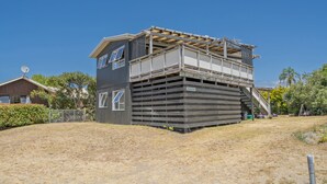 A two-story building with a flat roof and a balcony on the upper floor. - The Black Shack - Cooks Beach Holiday Home (Cooks Beach)