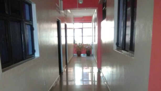Un pasillo con piso de baldosas, pared roja y ventanas a un lado.