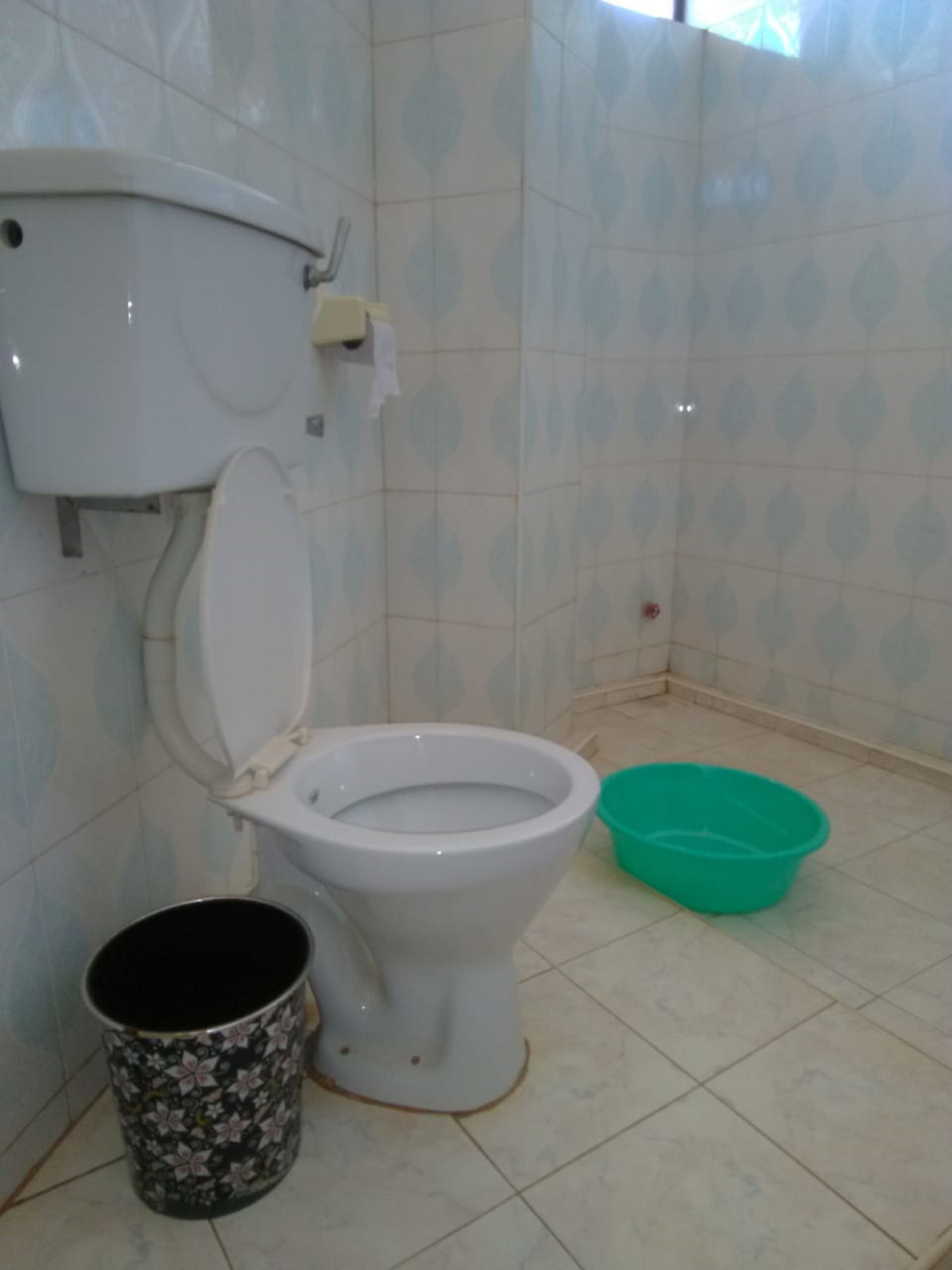 Um banheiro com vaso sanitário, pia verde e lixeira.