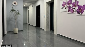 Un pasillo moderno con una planta en maceta, un reloj y decoración de orquídeas en la pared.