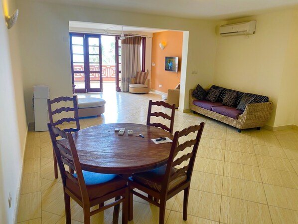 A dining area with a round table and chairs, a sofa, and a refrigerator.