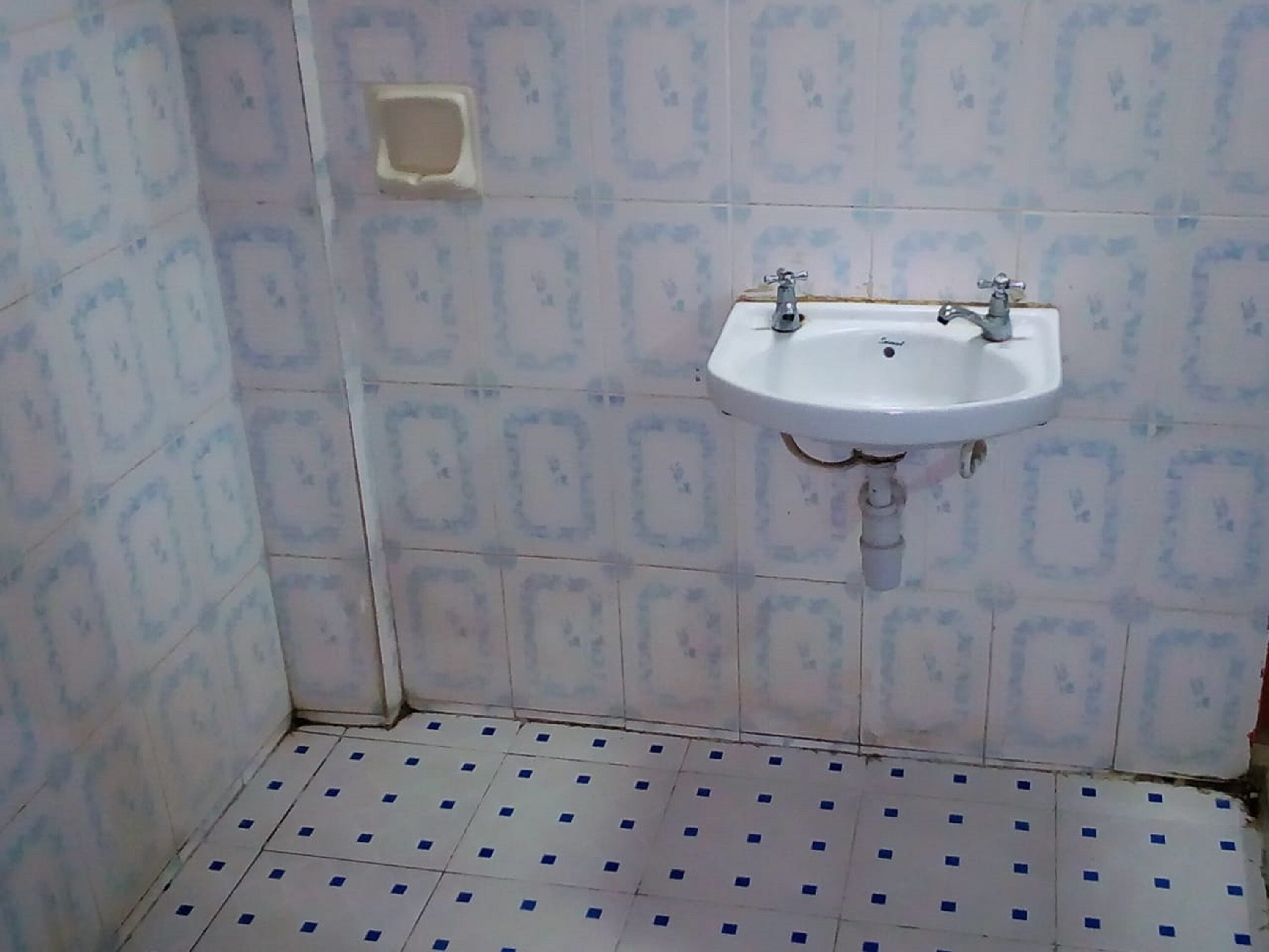 Ein Badezimmer mit einem weißen Waschbecken, gefliesten Wänden und einem Musterfliesenboden.