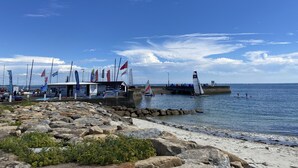 Ein Yachthafen mit vertäuten Booten, einer Anlegestelle und einer felsigen Küste.