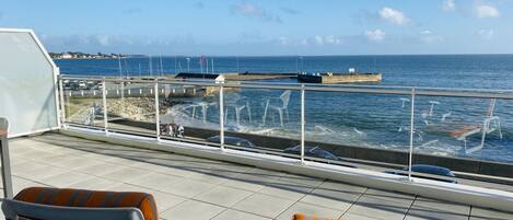 Una terraza con dos sillas y vista al mar.