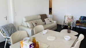 Ein modernes Wohnzimmer mit einer Couch, einem Esstisch und Stühlen. Auf dem Tisch steht eine Vase mit Blumen.
