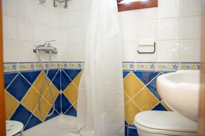 A bathroom with a shower, a toilet, and a sink.