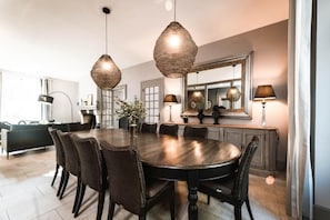 A dining area with a round table, six chairs, and hanging pendant lights. - Le Clos Saint Sulpice (Fossé)