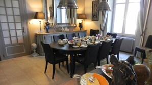 A dining area with a round table set for breakfast, featuring plates of food, cutlery, and a decorative horse sculpture. - Le Clos Saint Sulpice (Fossé)