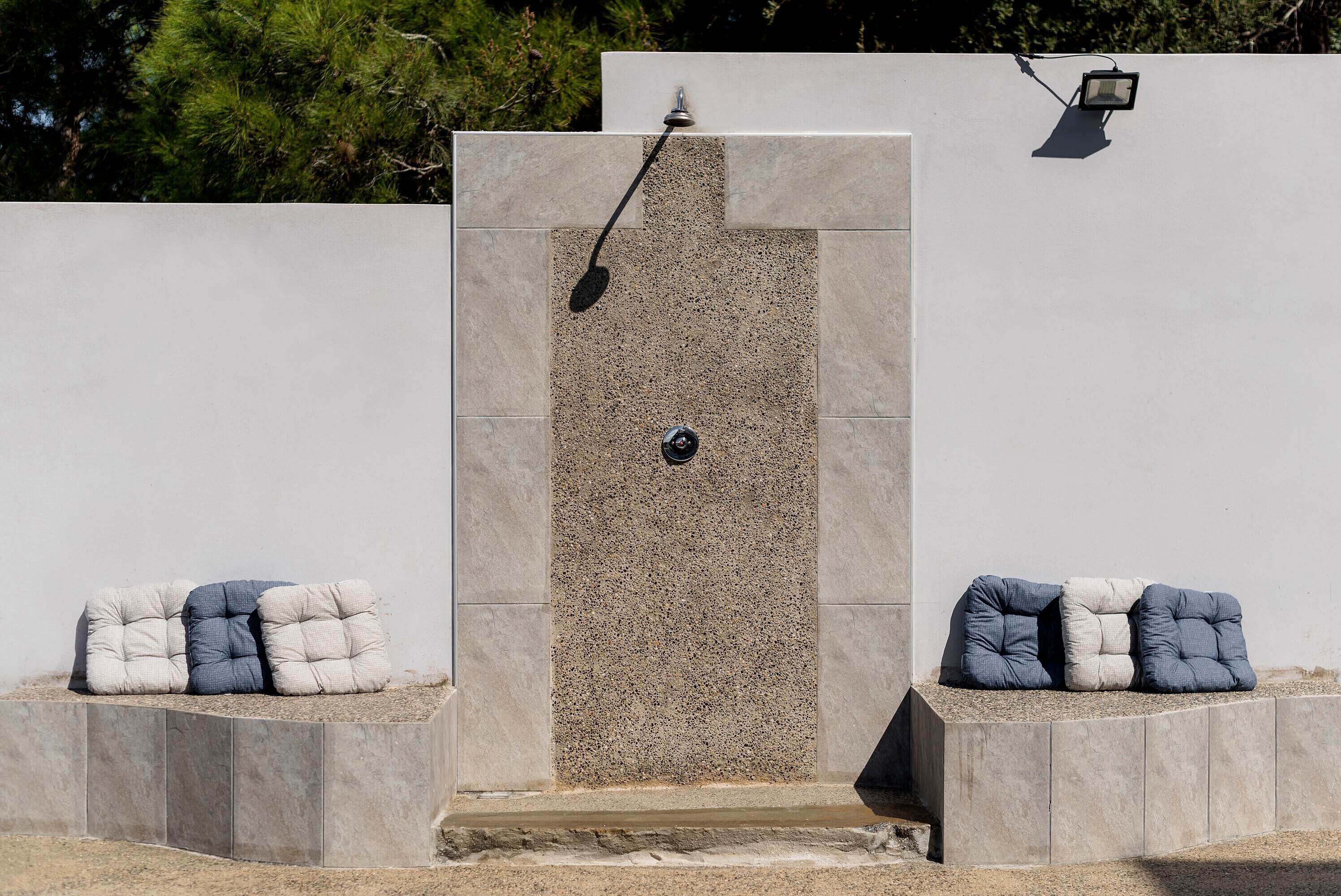 Une douche extérieure moderne avec une façade en pierre, un bec de douche et un panneau de commande.