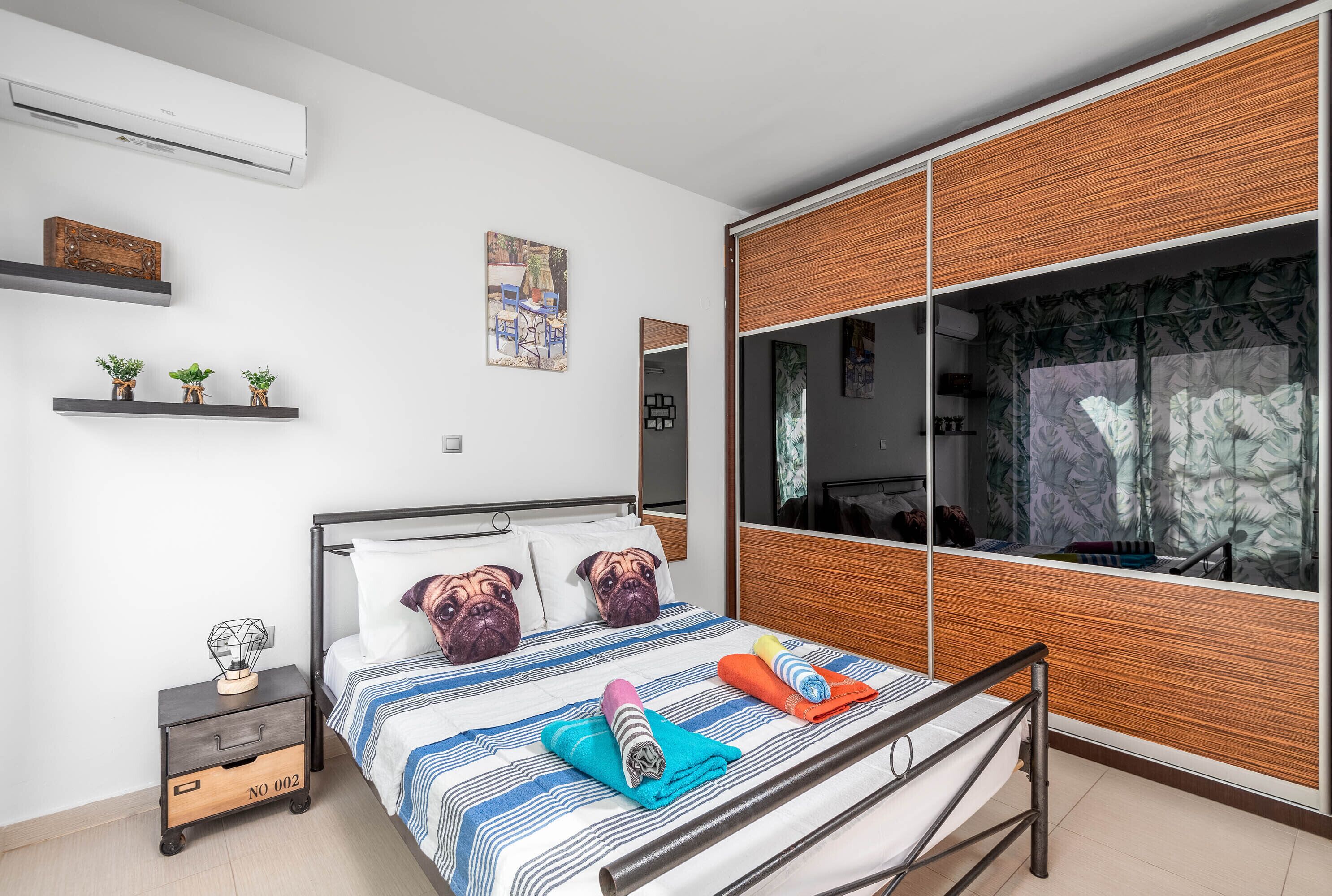 A modern bedroom with a bed, a nightstand, a wardrobe, and a large window with curtains.