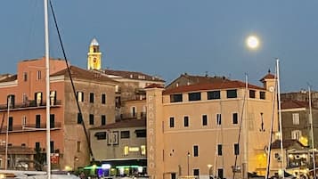 Un port de plaisance avec des bateaux amarrés, un bâtiment doté d’un clocher et un ciel nocturne dégagé.