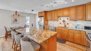 A modern kitchen with granite countertops, wooden cabinets, and a built-in dishwasher. - 1 Step Closer 2 Bedroom Villa by RedAwning (Holmes Beach)