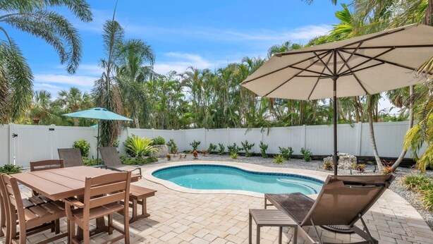 A backyard with a swimming pool, patio furniture, and a white fence. - 1 Step Closer 2 Bedroom Villa by RedAwning (Holmes Beach)