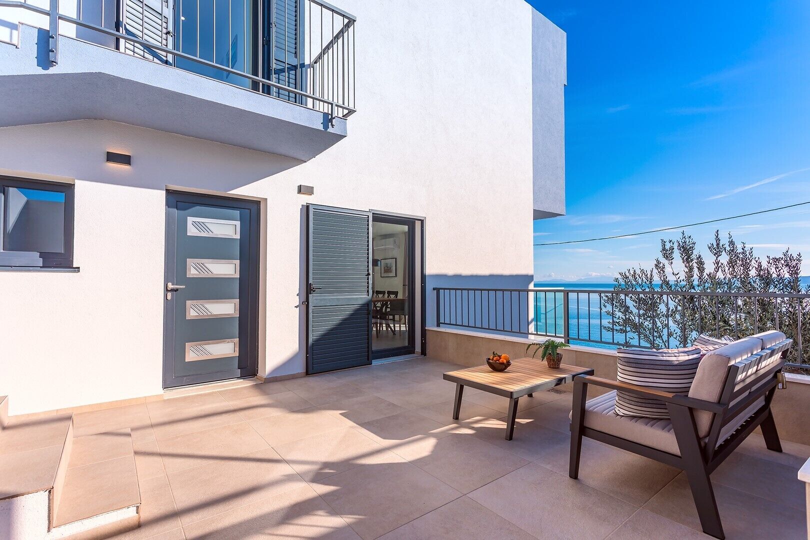Ein Balkon mit Tisch und Stühlen, einer Tür und Blick auf das Meer.