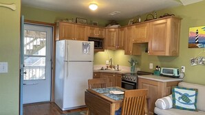 A compact kitchen with wooden cabinets, a refrigerator, a microwave, and a stove. - 19 Oceans Door West Studio Bedroom Condo by RedAwning (Hatteras)