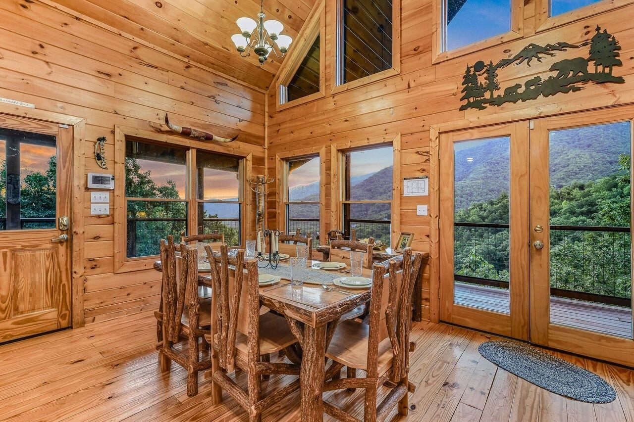 Interno in legno con tavolo da pranzo per sei persone, ampie finestre e vista su un paesaggio montuoso.