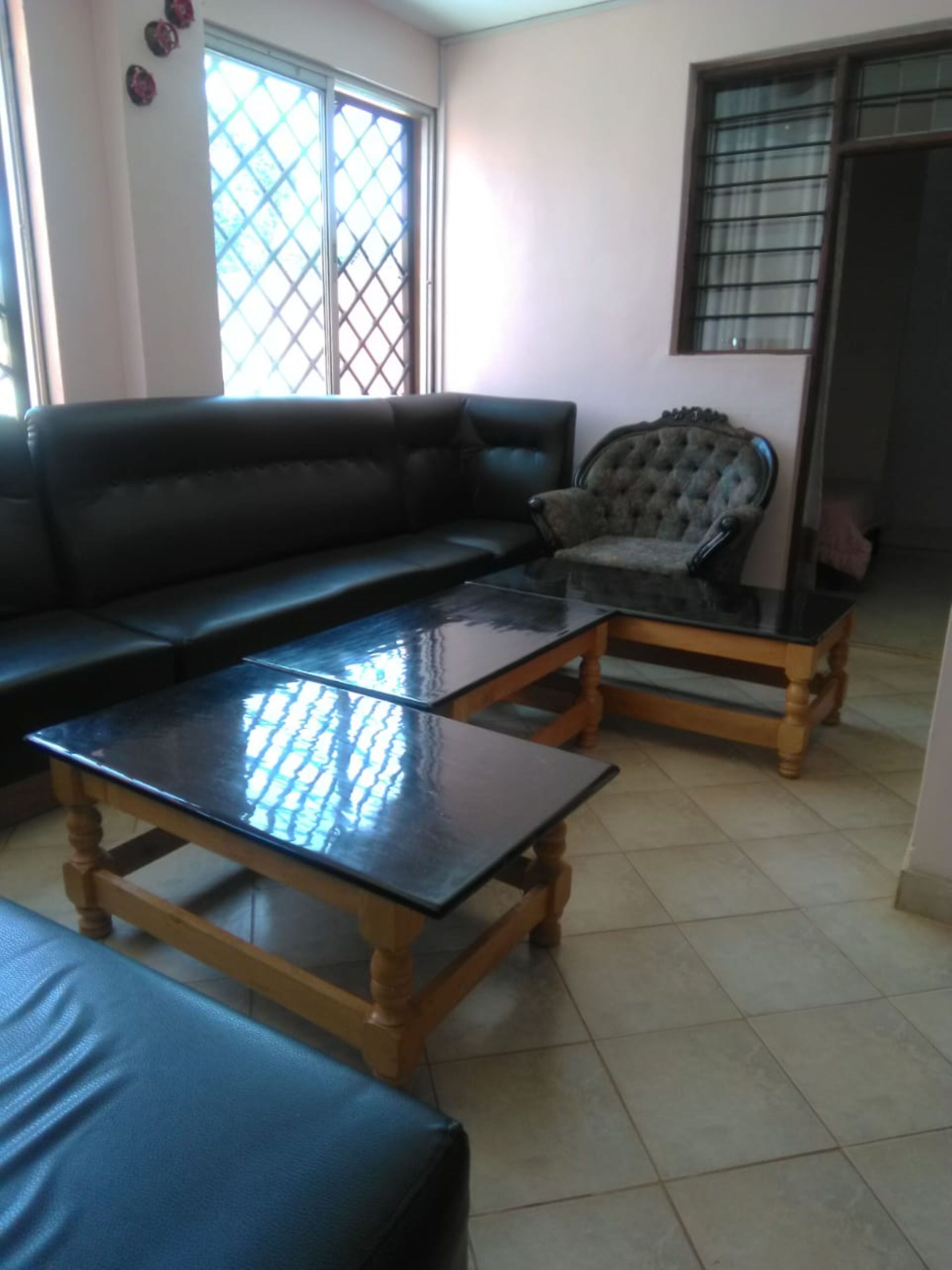 A living room with a black leather sofa, a wooden coffee table, and a matching armchair.
