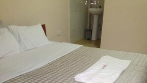 Una cama bien hecha con una colcha estampada y una toalla blanca doblada sobre la cama.