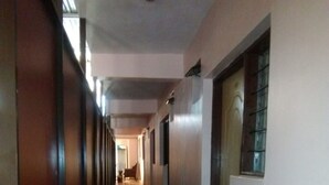 Un pasillo largo y estrecho con suelo de baldosas y paneles de madera en un lateral.